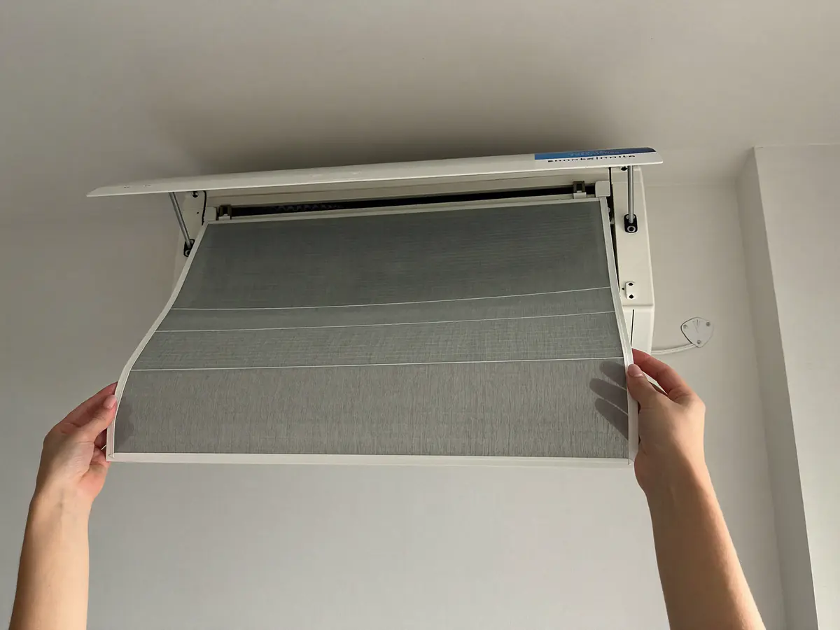 Handen houden een stoffilter uit een binnenunit vast