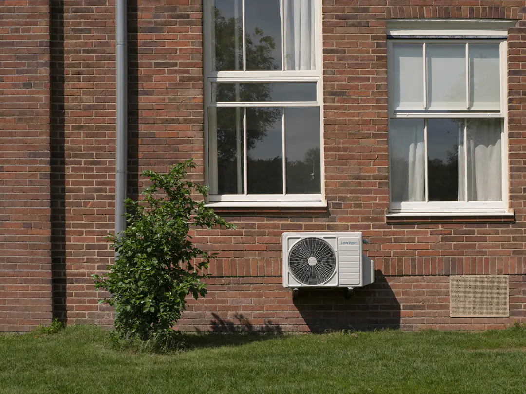 Buitenunit aan een bakstenen gevel van een woning