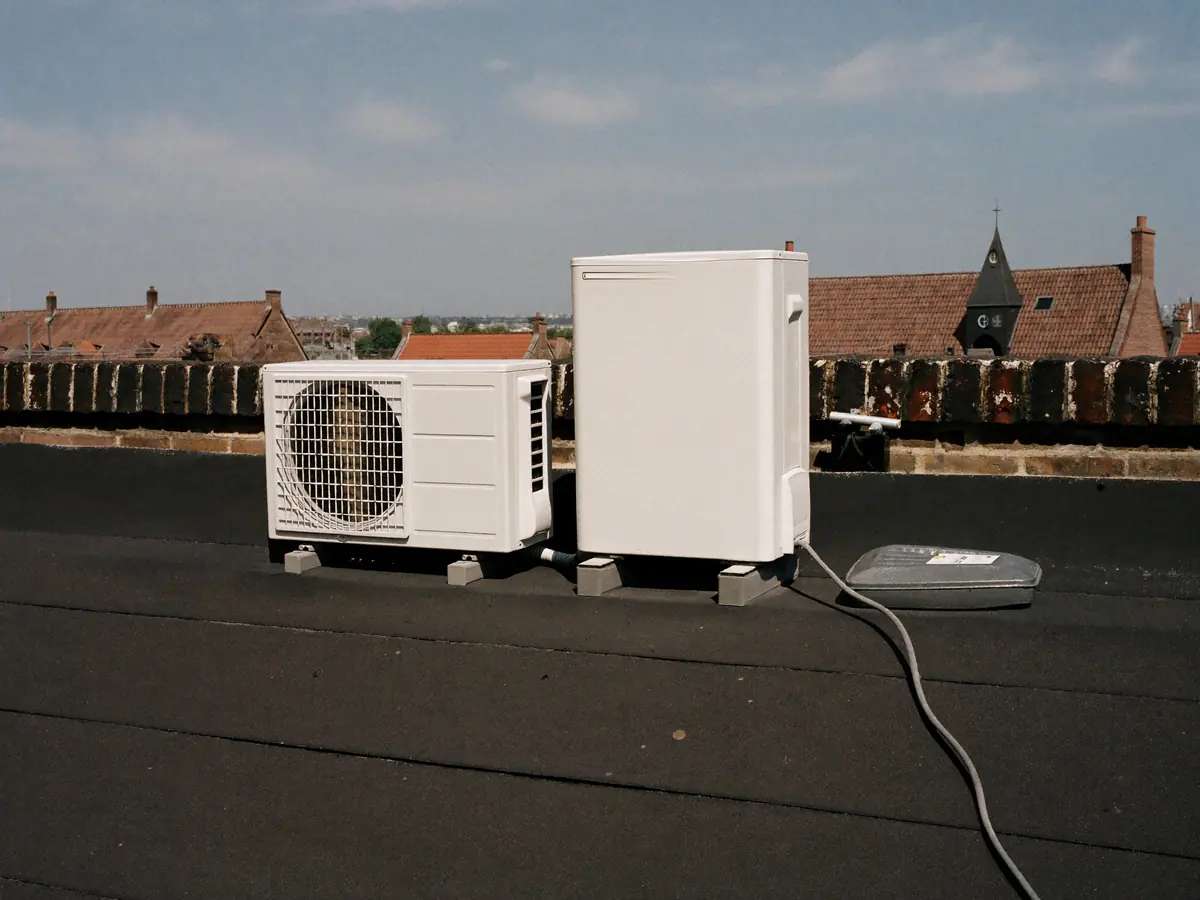 Twee buitenunits op een plat dak achter een lage borstwering