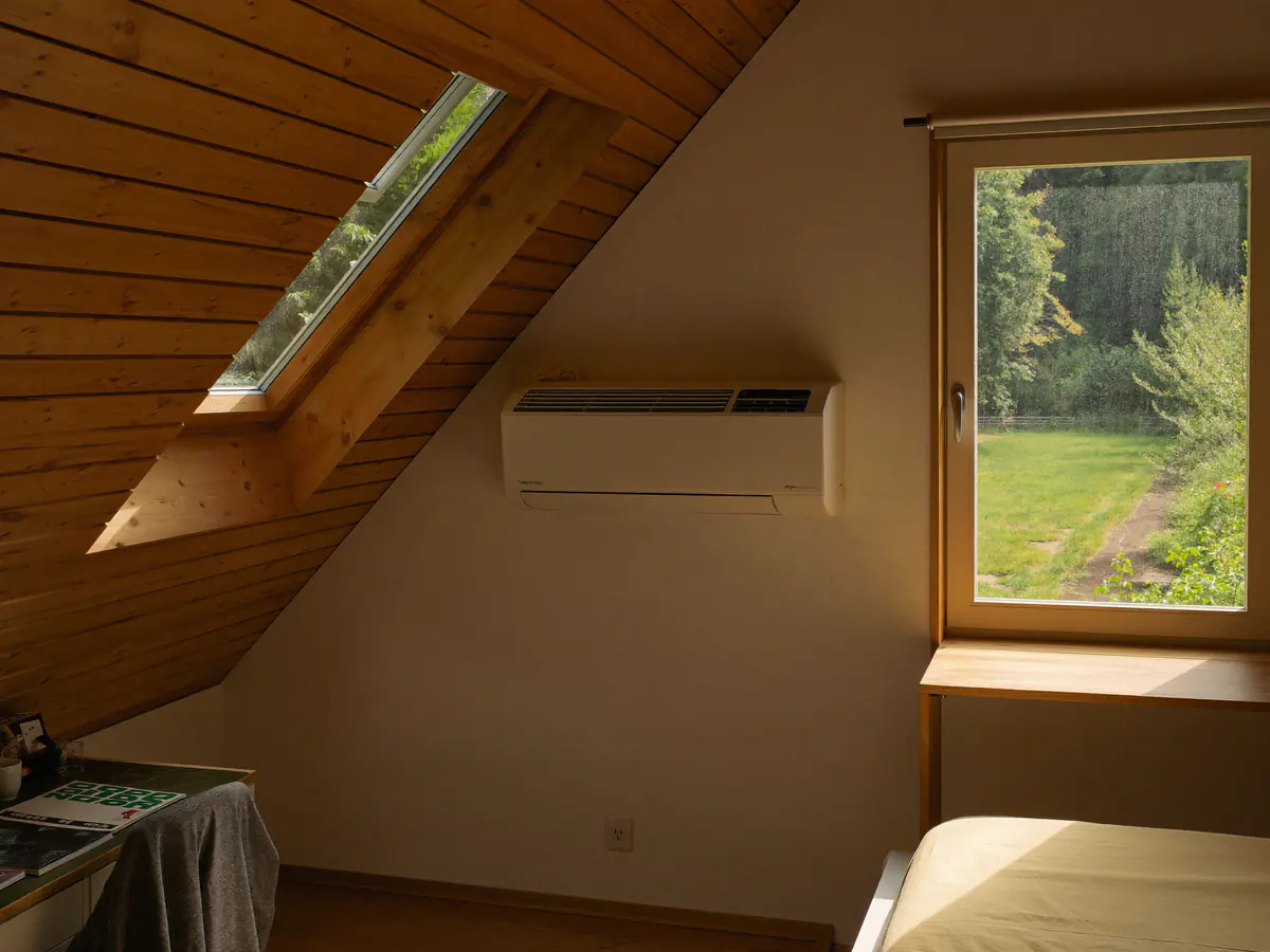 Zolderkamer met een binnenunit aan de rechte wand